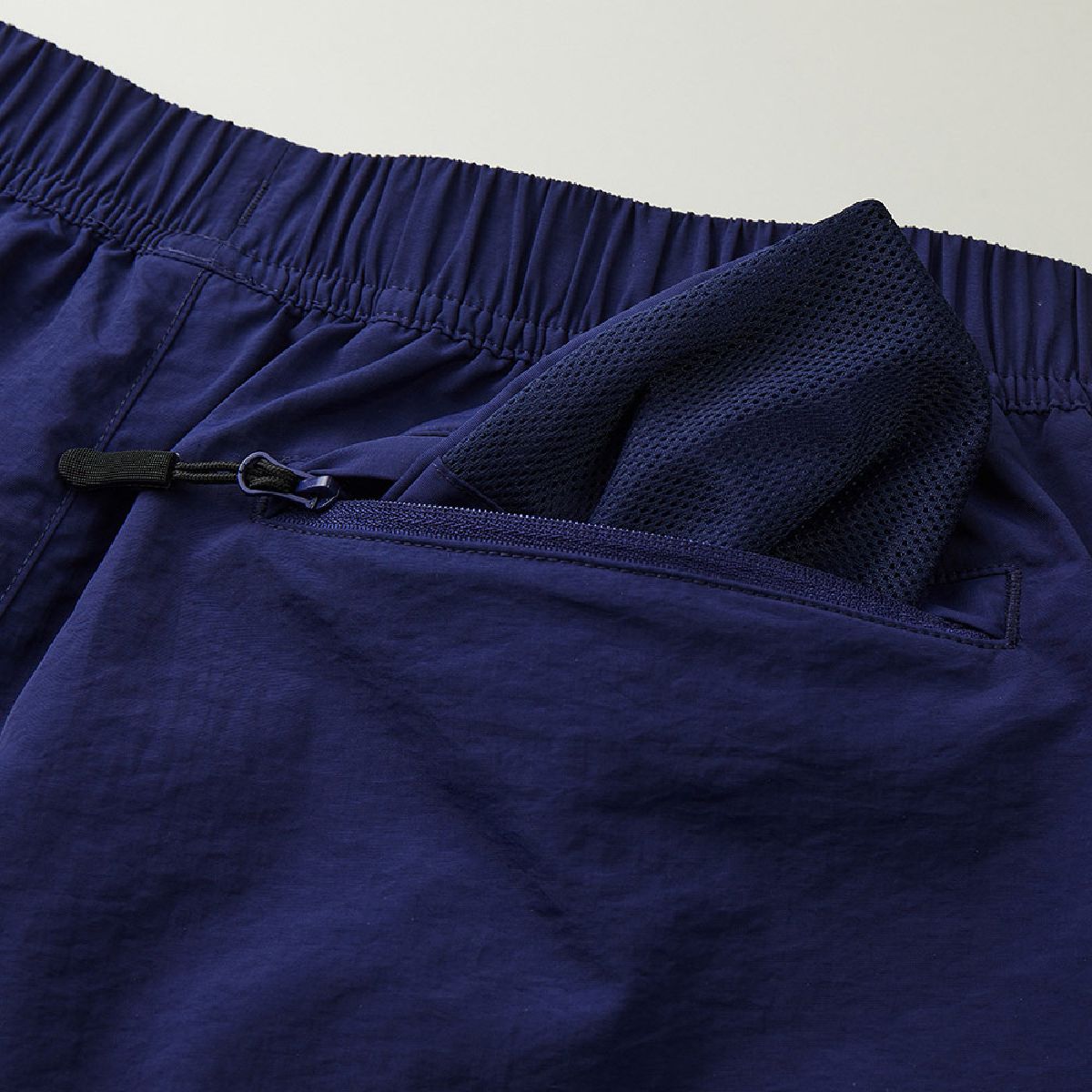 The hip pocket opening is lined with a coil zipper, and the bag fabric is made of mesh.