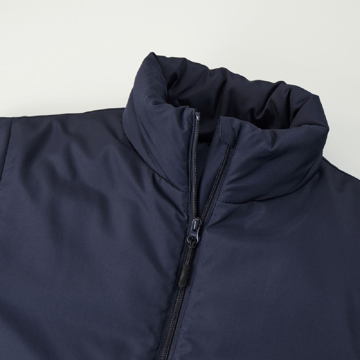 The neckline features a stand-up collar design to block out the wind, complete with a chin guard.