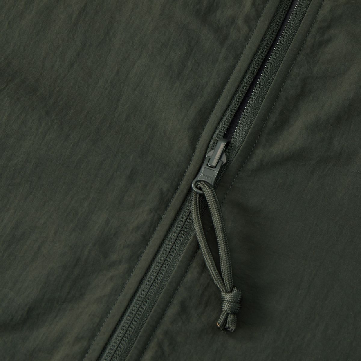 The zipper is a YKK model featuring a rotating automatic-locking slider, and the paracord pull tab matches the color of the garment body.